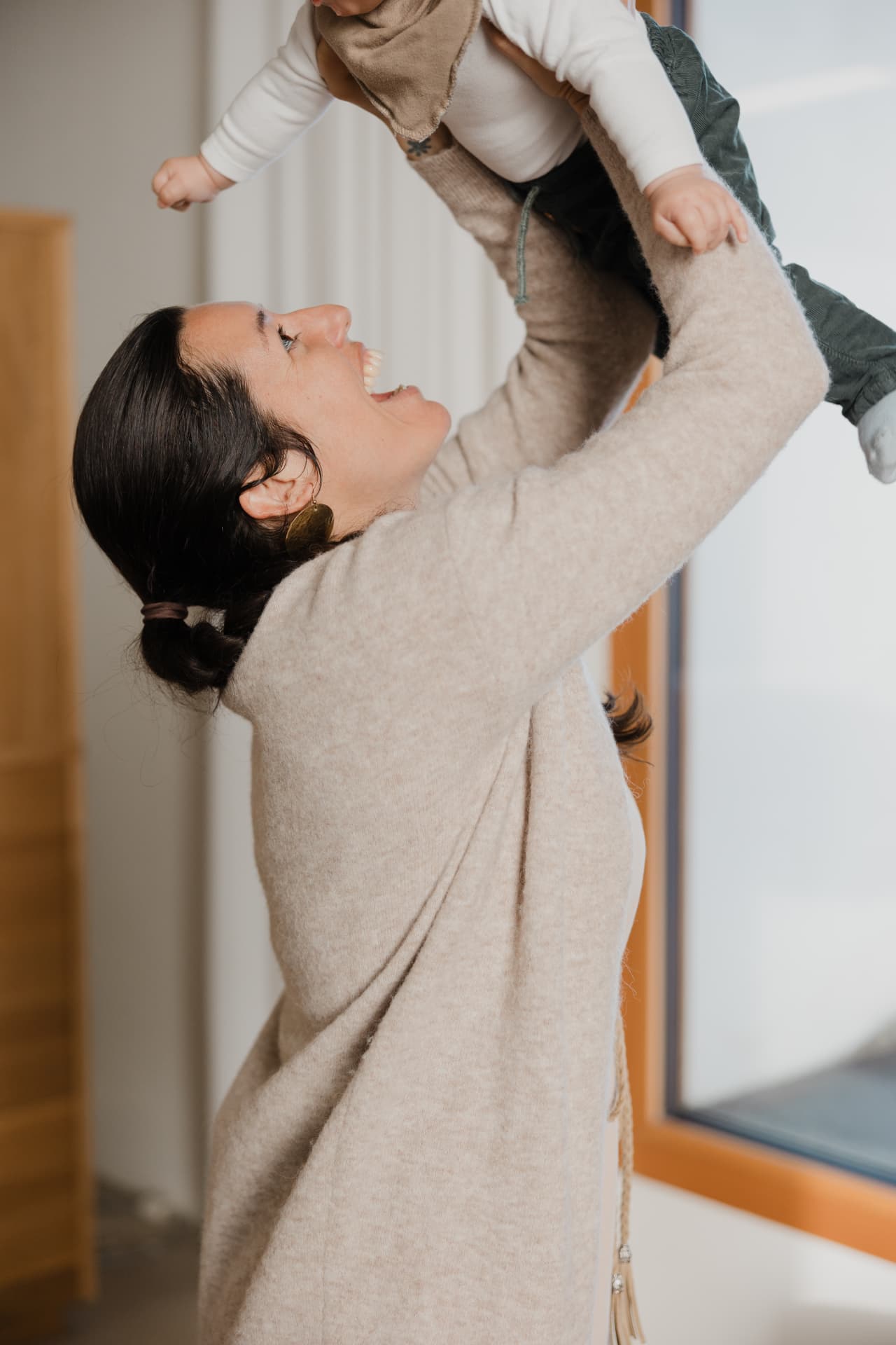Verena Metzler hebt fröhlich ein Baby hoch